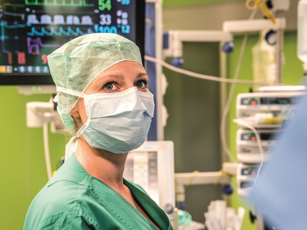 Eine medizinische Fachkraft mit Maske vor einem Herzmonitor im Operationssaal, Abteilung Anästhesiologie und Intensivmedizin, Albertinen Krankenhaus, Hamburg-Schnelsen